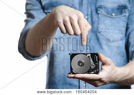 Man's hand holds a 2.5 inch hard drive. He's points to the hard disk. View of the backside HDD, from the PCB. Isolated on white background.