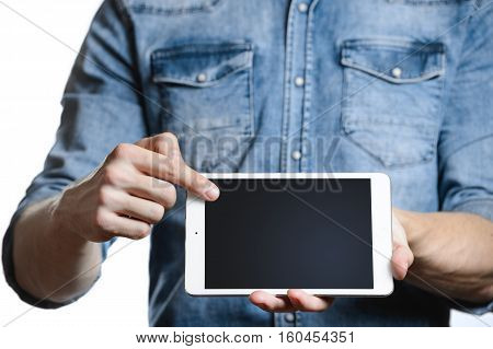 Casual man in denim shirt showing digital tablet computer screen in hands. Isolated on white. Clipping path for display included. He points a finger at the display.