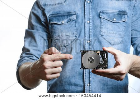 Man's hand holds a 2.5 inch hard drive. He's points to the hard disk. View of the backside HDD, from the PCB. Isolated on white background.