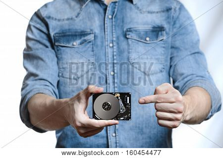 Man's hand holds a 2.5 inch hard drive. He's points to the hard disk. View of the backside HDD, from the PCB. Isolated on white background.
