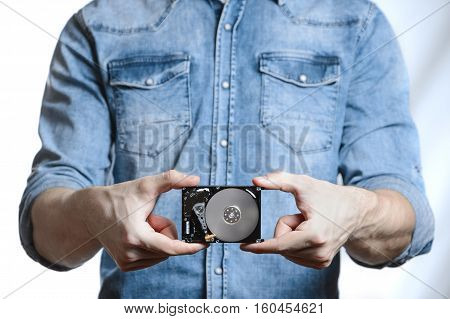 Man's hand holds a 2.5 inch hard drive. He's points to the hard disk. View of the backside HDD, from the PCB. Isolated on white background.