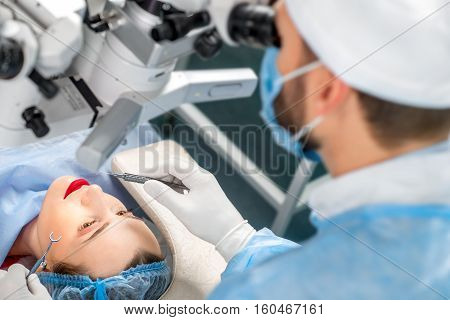 Surgion operating eye of female patient with surgical tools in the operating room