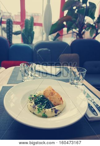 Fried black cod fillet with potato mash on restaurant table