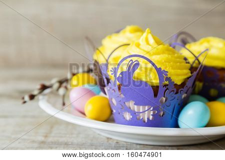 Easter cupcakes with eggs and flaffy willow, wood background
