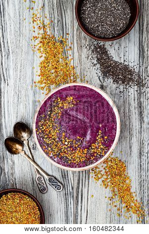 Acai breakfast superfoods smoothies bowl with chia seeds bee pollen toppings. Immune boosting anti inflammatory smoothie with turmeric honey and maca powder. Overhead top view flat lay copy space