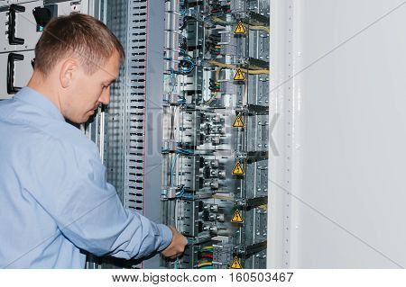 Electrician near the low voltage cabinet. Uninterrupted power supply. Electricity.