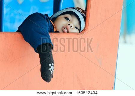 little boy on the Playground in winter was tired and lay down to rest