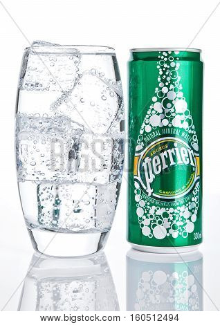 LONDON UK - DECEMBER 06 2016: Glass with ice and tin of Perrier sparkling water. Perrier is a French brand of natural bottled mineral water sold worldwide.