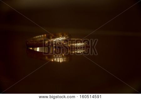 Wedding rings on the table with reflection and bokeh