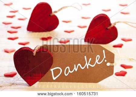Label With German Text Danke Means Thank You. Many Red Heart. Wooden Rustic Or Vintage Background.