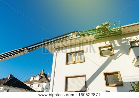 View from below to the modern hydraulic mobile construction platform elevated on the last floor of a house with construction worker preparing to to work