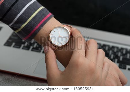 Girl's hand with wrist watch in front of notebook computer