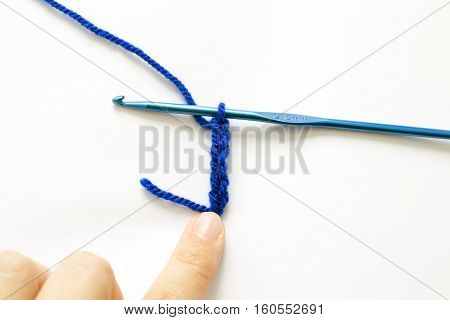Crochet pattern and metal crochet hook on white background