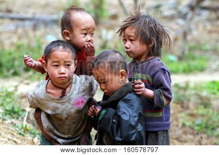 HA GIANG, VIETNAM - FEB 14, 2012: Poor and hungry Hmong children sharing candy (as a gift) from tourist on a cold day of winter in Dong Van district. Dong Van rocky plateau is a well known geopark.