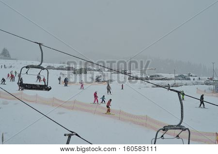 BUKOVEL, UKRAINE - December 2, 2016: Snowboarder and skiers enjoying on slopes of ski resort Bukovel. Bukovel is the most popular ski resort in Ukraine. Ski season and Winter sports concept