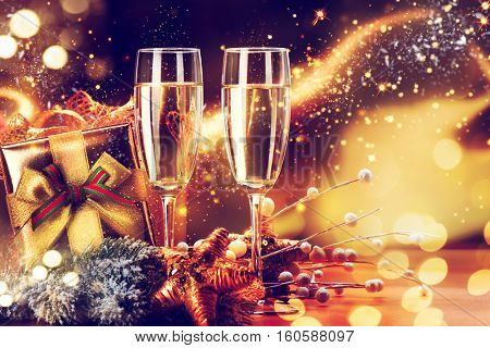Christmas and New Year Celebration. Two Champagne Glasses and Gifts over Golden Blinking Holiday Background. Christmas party, Winter Holiday party, Xmas decoration.