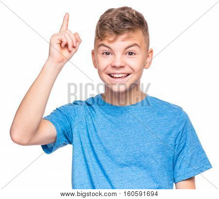 Cute teen boy pointing up, gesturing idea or doing number one gesture. Conceptual half-length emotional portrait of caucasian teen boy wearing blue t-shirt. Handsome child, isolated on white background.