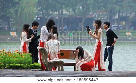 HANOI, VIETNAM - NOV 27, 2013: A group of unidentified newly graduated students posing on the bank of Hoan Kiem lake.