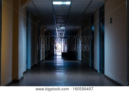 Long dark deserted corridor at the end of the corridor a window with bright light on each side of corridor doors top Shine dim ceiling lights hopelessness a road to nowhere
