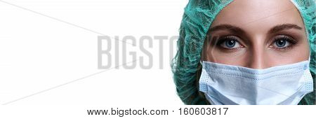 Female doctor face wearing protective mask and green surgeon cap closeup isolated on white background. Save patient life copy space banner laboratory 911 medic help concept. Letterbox view