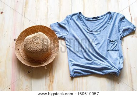 fashionable women's clothes on a wood background Gray T-shirt Woven hat with natural top view.