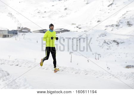 young healthy sport man running in snow mountains in trail runner hard workout in energy and endurance concept with a beautiful cold winter background