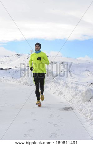 young healthy sport man running in snow mountains in trail runner hard workout in energy and endurance concept with a beautiful cold winter background