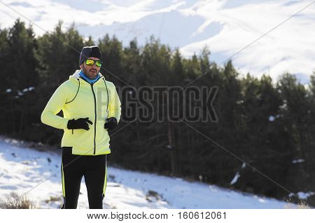 young healthy sport man running in snow mountains in trail runner hard workout in energy and endurance concept with a beautiful cold winter background