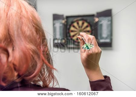 Closeup of young woman's head and hand throwing a dart