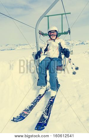 Happy female skier riding a lift. Skiing in sunny weather.