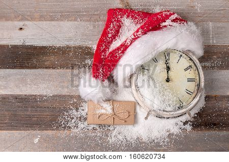 Christmas decoration Clock with Santa Claus hat and gift on wooden background