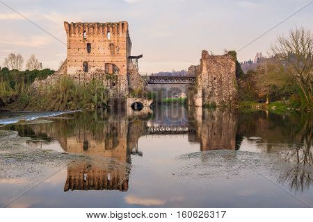 Reflections of ancient bridge in water of Mincio River at Borghetto Valeggio sul Mincio lovely town in Northern Italy.