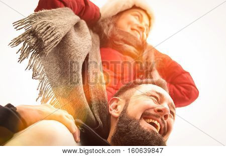 Happy couple of travelers in love enjoying winter time outdoor - Handsome hipster man with young woman on piggyback balance - Relationship concept with boyfriend and girlfriend on warm sunshine filter