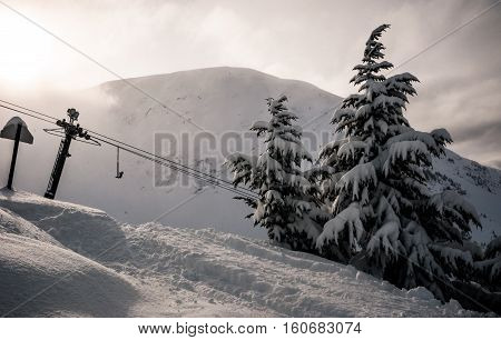 Winter wonderland in Alaska with Chugach Mountains in the background and a Ski lift taking winter sport athletes and skiers and snowboarders to the top of a snow covered winter wonderland in Girdwood , Alaska , USA