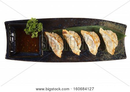 Yaki gedza with sauce in a ceramic pot on a white background