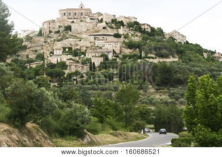 cars driving on road below old hill town of mougins near cannes in southern france