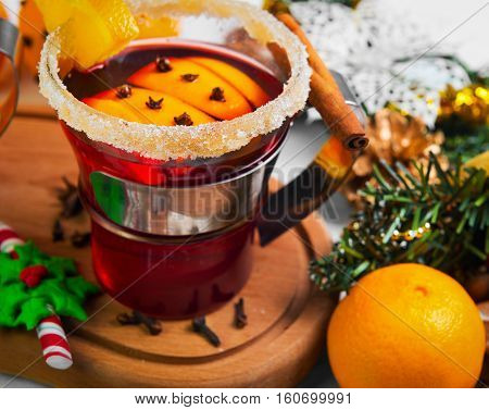 Winter Christmas drink hot mulled wine. Ingredients for mulled wine oranges cinnamon anise. Glasses with mulled wine decorated with sugar. Christmas gift with sweets nuts. White wooden background.