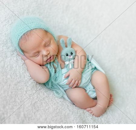 lovely sleeping baby with blue hat, panties and toy on white blanket