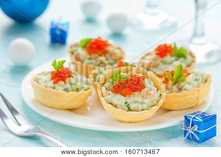 Festive Christmas appetizer tartlets stuffed with salmon salad and red caviar - tasty snack for christmas or new year dinner holiday food recipe