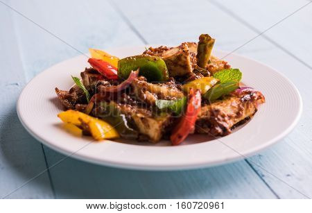 Spicy Paneer or chilli paneer or cottage cheese, served in white Dish with capsicum and onion, favourite indian starter menu, selective focus