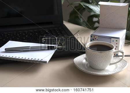 Work desk with laptop computer and hot coffee cup with defocused background