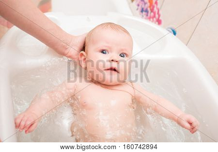 Baby with blue eyes bathed in the bath
