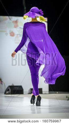 Beautiful young blonde woman in purple dress covered oriental veil