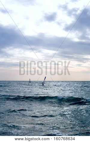 Group of windsurfers on boards in wavy sea. Lifestyle and sport completition concept. Group of people. Fun and leisure activity. Vertical composition.