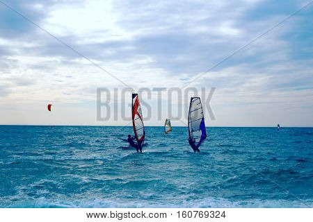 Group of windsurfers on boards in wavy sea. Lifestyle and sport completition concept. Group of people. Fun and leisure activity.