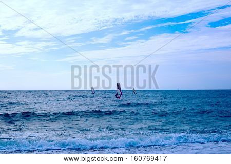 Group of windsurfers on boards in wavy sea. Lifestyle and sport completition concept. Group of people. Fun and leisure activity.