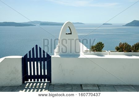 blue gate wicket and white fence. Mediterranean sea and Santorini caldera  on the background. concept of leasure, freedom, luxury