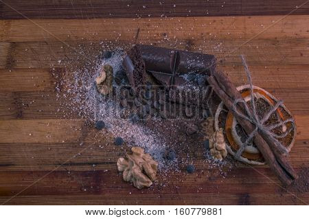 composition of chocolate, sugar, nuts and dried oranges on a wooden board
