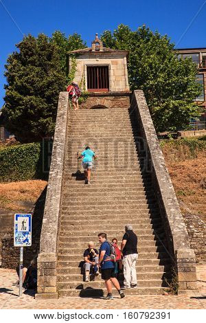 PORTOMARIN SPAIN - AUGUST 12: Pilgrims ascending the Roman staircase on August 12 2016