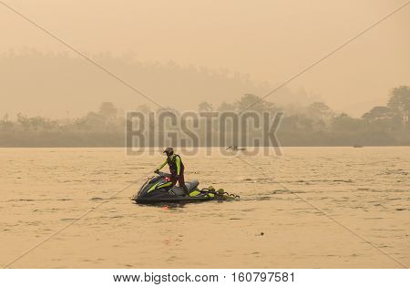 Lifeguard on jetskis with two sporters grab in stern floating in river in triahlonThailand.